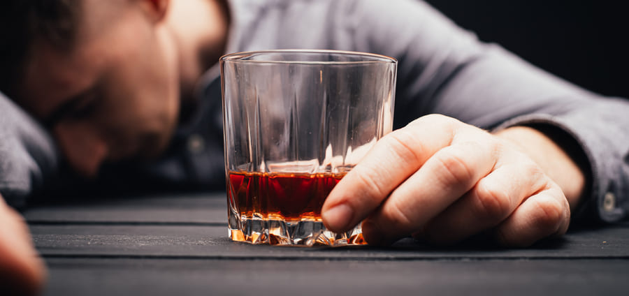 Пьяный мужчина со стаканом в руке спит за столом