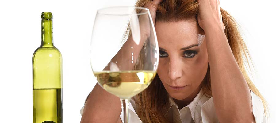 грустная женщина смотрит на бокал с вином